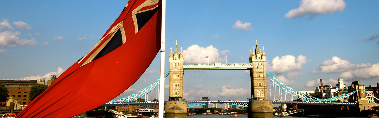 View of Tower Bridge from the River Thames. A flag is in the foreground on the boat.